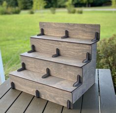 three tiered wooden box sitting on top of a wooden table in front of a grassy field