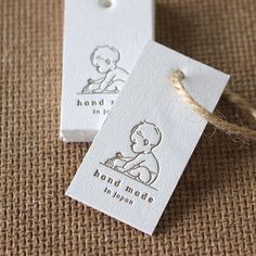 two tags with the words hand made on them are sitting next to twine cord