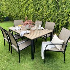 an outdoor dining table with four chairs and a vase filled with flowers on top of it