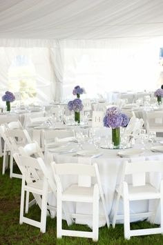 tables and chairs are set up in the grass for an outdoor wedding reception with white linens and purple flowers