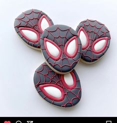 three decorated cookies sitting on top of each other in the shape of spiderman's eyes