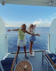 two women on a boat in the ocean with their arms out and one woman is holding her hands out