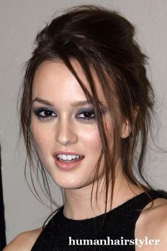 a close up of a person with makeup on and hair in a messy top knot