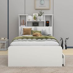 a white bed sitting next to a shelf filled with pillows and other items on top of it