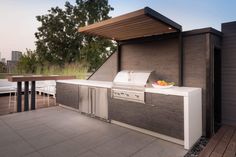 an outdoor kitchen with grill, sink and table