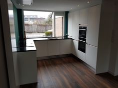 an empty kitchen with wood floors and white cabinets