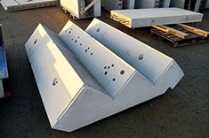 several large white boxes sitting next to each other on top of a cement ground with people standing around them