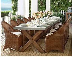 an outdoor dining area with wicker chairs and a table set for eight on the porch