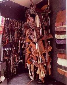 the inside of a storage area with many different types of saddles hanging on it