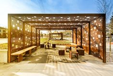 an outdoor seating area with wooden benches and pergolated walls