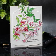 a close up of a card with flowers on it and a pen next to it