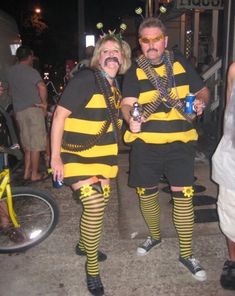 two people dressed in bee costumes standing next to each other on the street at night