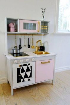 a pink and white play kitchen with gold accents