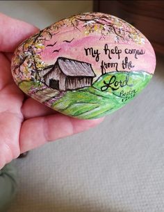 a hand holding a painted rock with the words, my help comes from the lord