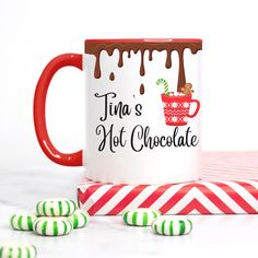 a red and white coffee mug sitting on top of a table next to green and white candy