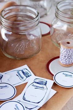 mason jars with labels and twine spools sitting on a table next to each other