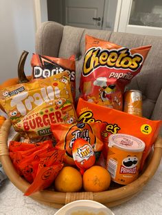 a basket filled with snacks sitting on top of a table next to a bowl of oranges