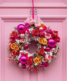 a pink door with a wreath hanging on it