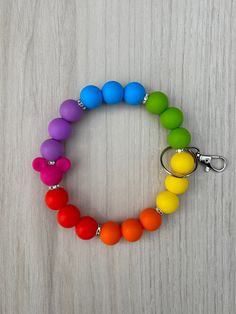 a multicolored beaded bracelet on a wooden table with a keychain