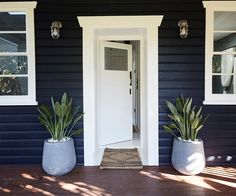 two large planters are on the front steps of a house with a white door