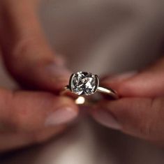 a close up of a person holding a ring with a diamond in it's middle