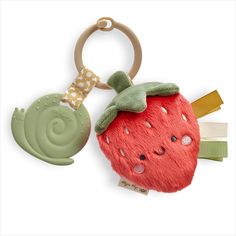 a stuffed strawberry keychain with a cute green snail hanging from it's side