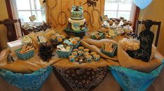 a table topped with lots of desserts and cupcakes next to a window