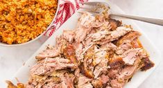 a white plate topped with meat next to a bowl of rice