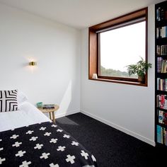 a bedroom with black and white bedding, bookshelves and a large window