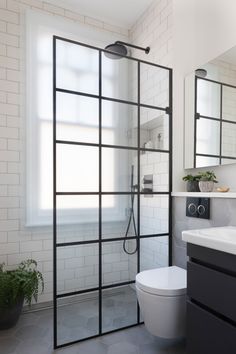 a bathroom with a toilet, sink and shower in it's own area next to a window