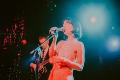 a woman in a red dress singing into a microphone