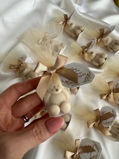 a person is holding a small teddy bear in front of some bows on a white cloth