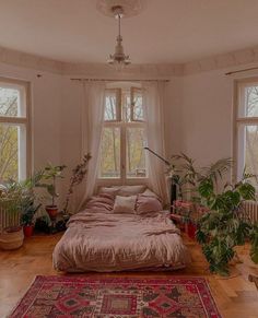 a bed room with a neatly made bed and lots of plants on the windowsill