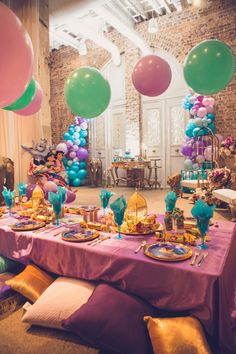 a table set up with balloons, plates and other decorations for a princess birthday party