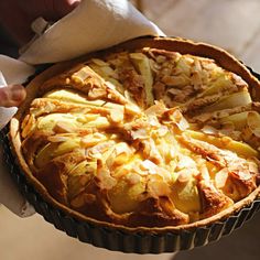 a person holding a pie with apples on it in their hand and napkins around the edges