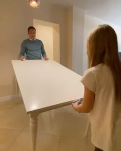 a man and woman standing in front of a white table with a light on it