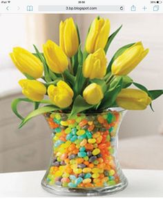 a vase filled with yellow tulips and candy