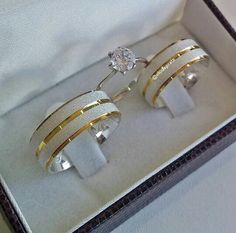 two gold and white rings in a box with a diamond on the top one ring