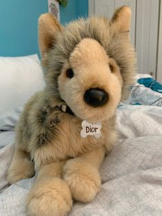 a stuffed animal that is sitting on a bed with a name tag in it's ear