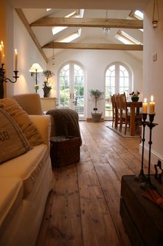 a living room filled with furniture next to a wooden floor covered in candles and windows