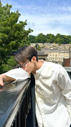 a young man leaning on the edge of a balcony