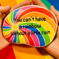 a rainbow painted rock with the words you can't have a rainbow without a little rain