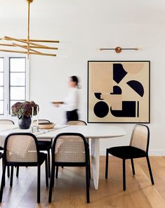 a dining room table with four chairs and a painting hanging on the wall above it