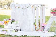 an outdoor area with flowers, birdcage and other decorations on the grass in front of a white fence