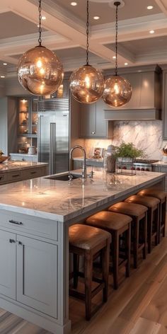 a kitchen filled with lots of counter top space and lights hanging from the ceiling above it