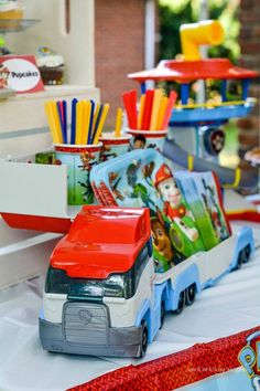 toy cars are lined up on a table with cupcakes and straws in them