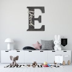 there is a white room with toys on the floor and a wooden letter that says e