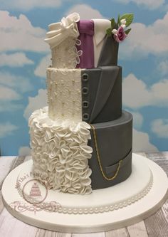 a three tiered wedding cake on top of a wooden table with clouds in the background