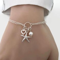 Perfect for a sea lover/sailor/beach wedding. A cute detailed starfish, tiny heart and freshwater pearl charm bracelet in sterling silver. Details: - Material metal: sterling silver - Starfish charm measures 15mm. - Heart charm measures approx. 7mm - Freshwater pearl measure 6-7mm - Adjustable Cheap Silver Charm Bracelet For Beach, Starfish Charm Bracelet As A Gift, Starfish Charm Bracelet Gift, Adjustable Starfish Charm Jewelry, Starfish Charm Bracelet As Gift, Star-shaped Bracelet With Starfish Charm Gift, Ocean-inspired Bracelet With Starfish Charm, Ocean-inspired Starfish Charm Bracelet, Adjustable Star-shaped Jewelry With Starfish Charm