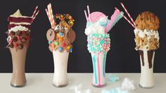 four ice cream sundaes in tall vases with candy and candies on them